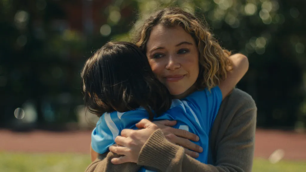 Tatiana Maslany in "Maximum Pleasure Guaranteed" embracing a child in a blue shirt.