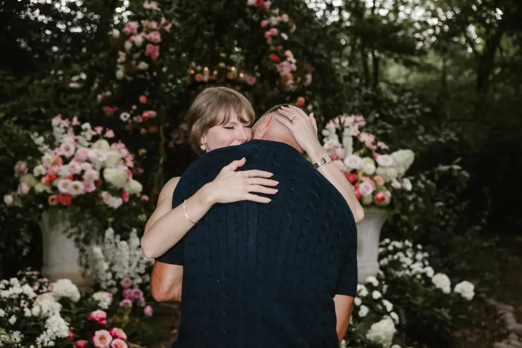 Taylor Swift hugging Travis Kelce, surrounded by flowers.