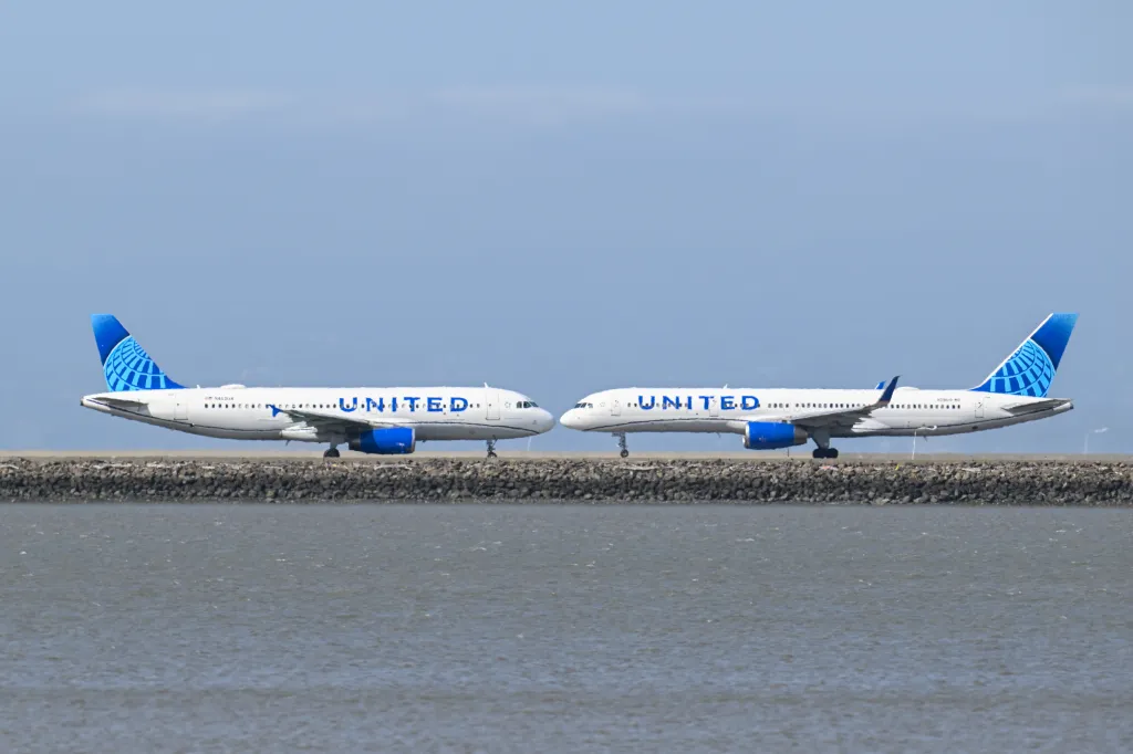 Two United Airlines passenger planes at San Francisco International Airport, with one taking off and the other landing.