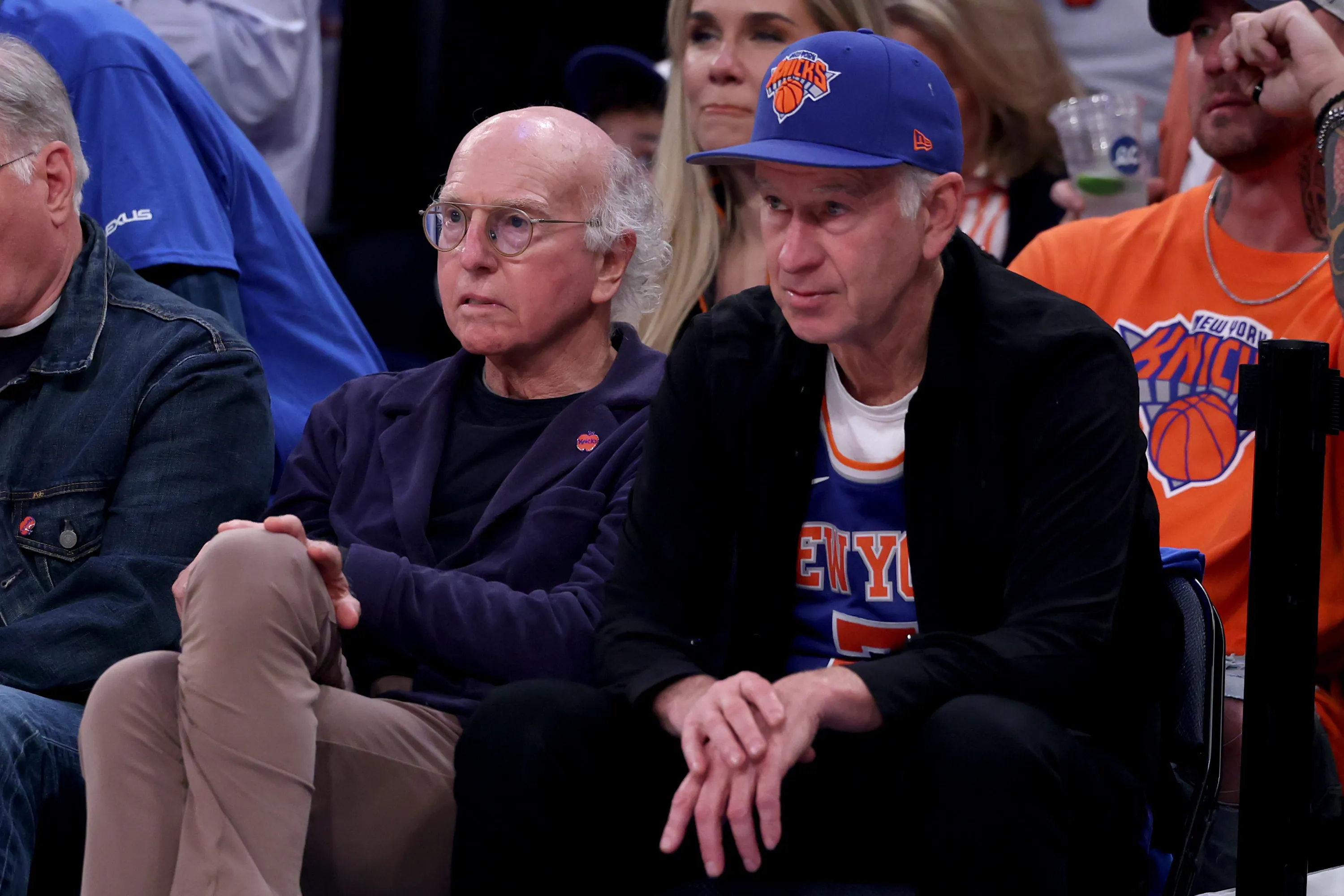 Larry David and John McEnroe watching an NBA game.