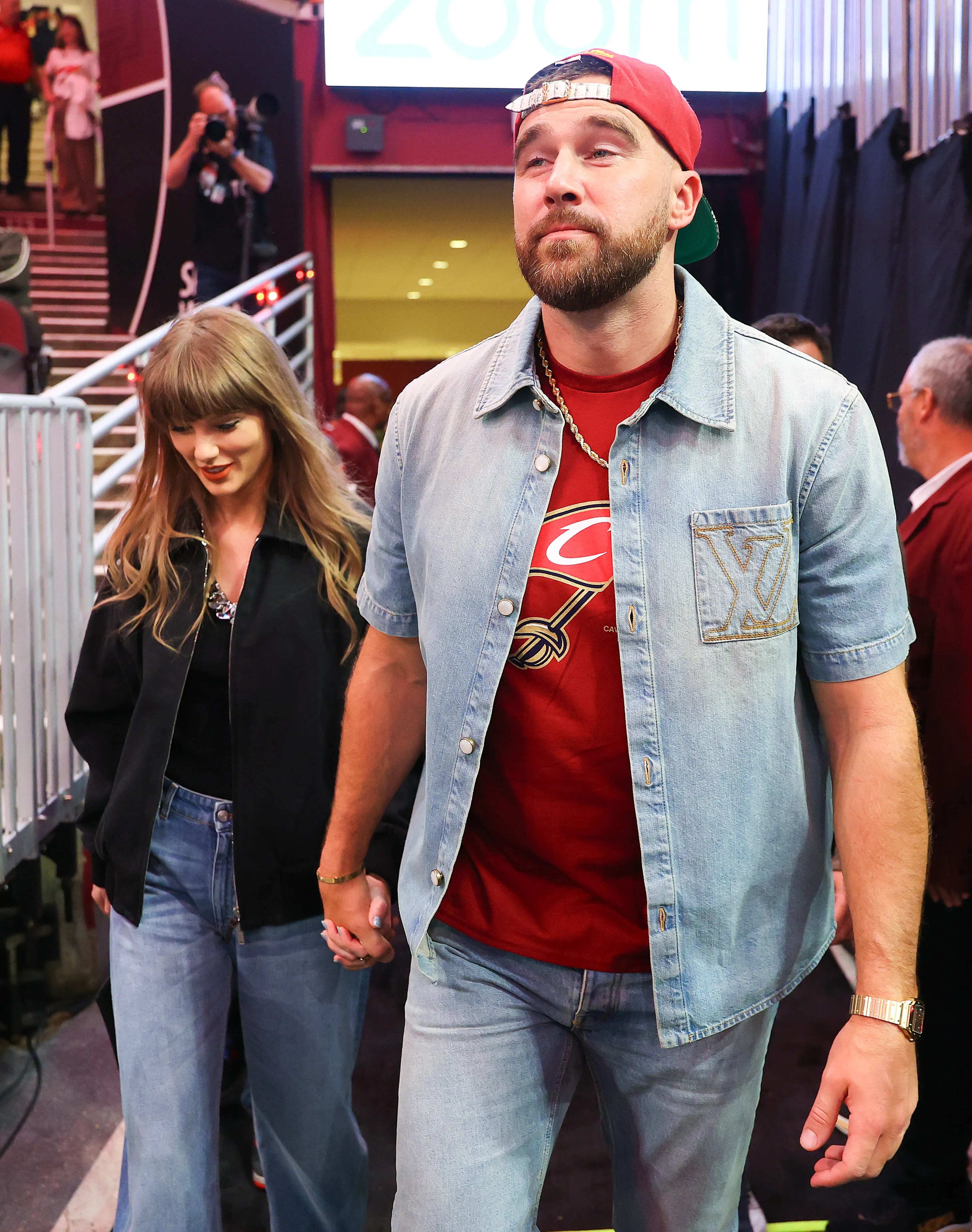 Taylor Swift and Travis Kelce walking hand-in-hand.