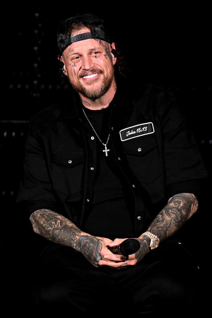 Jelly Roll performing in a black shirt, holding a microphone.