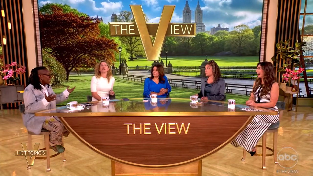 Five women sit at a curved desk with "THE VIEW" logo.
