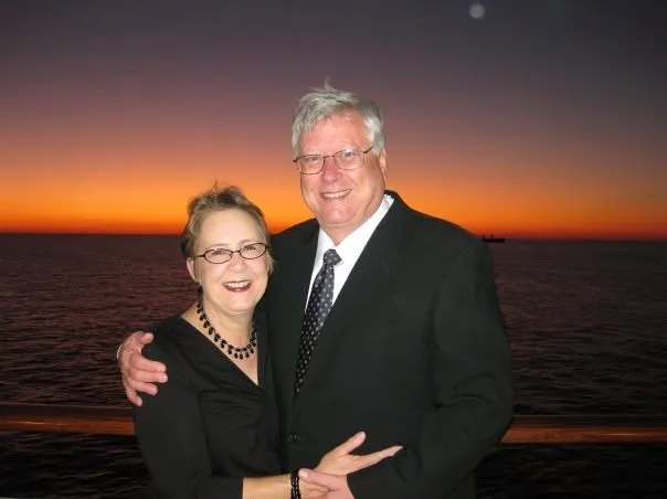 Former San Antonio Mayor William E. Thornton and a woman smiling at the camera with an orange sunset over the ocean in the background.