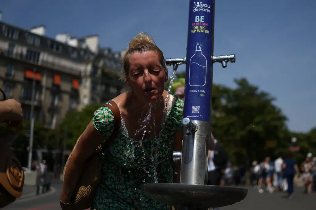 A woman cools off at a public fountain in Paris during a heatwave.