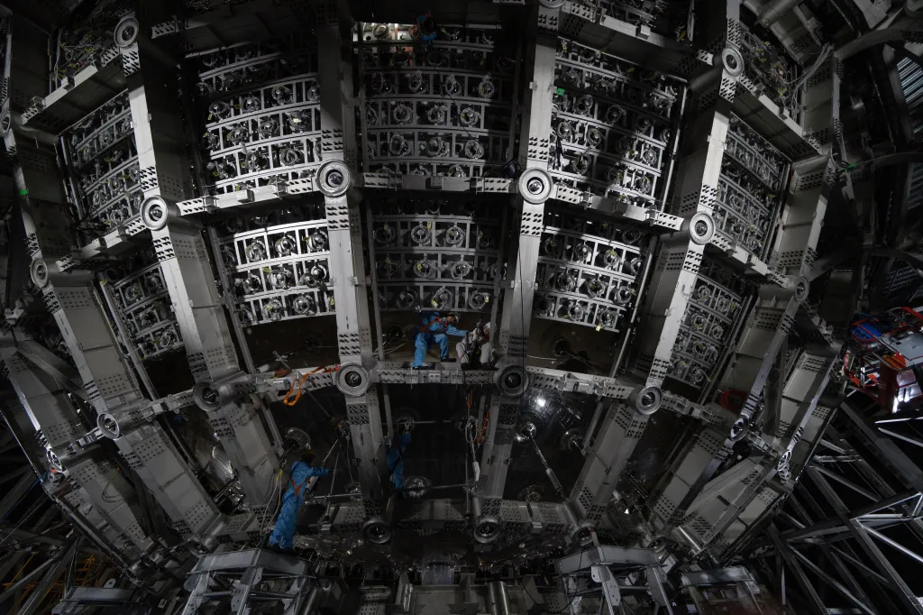 Workers labor on the underside of a cosmic detector.