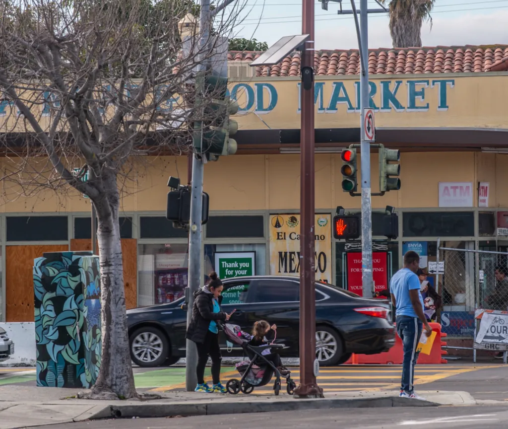 A market with two signs for "ATM Inside" and a street corner with people crossing the street.