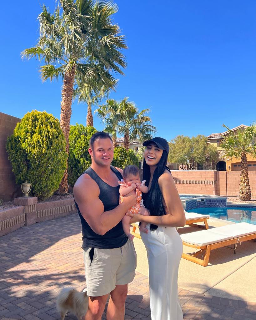 90 Day Fiancé' stars Patrick Mendes and Thais Ramone holding their baby in an outdoor patio next to a pool.