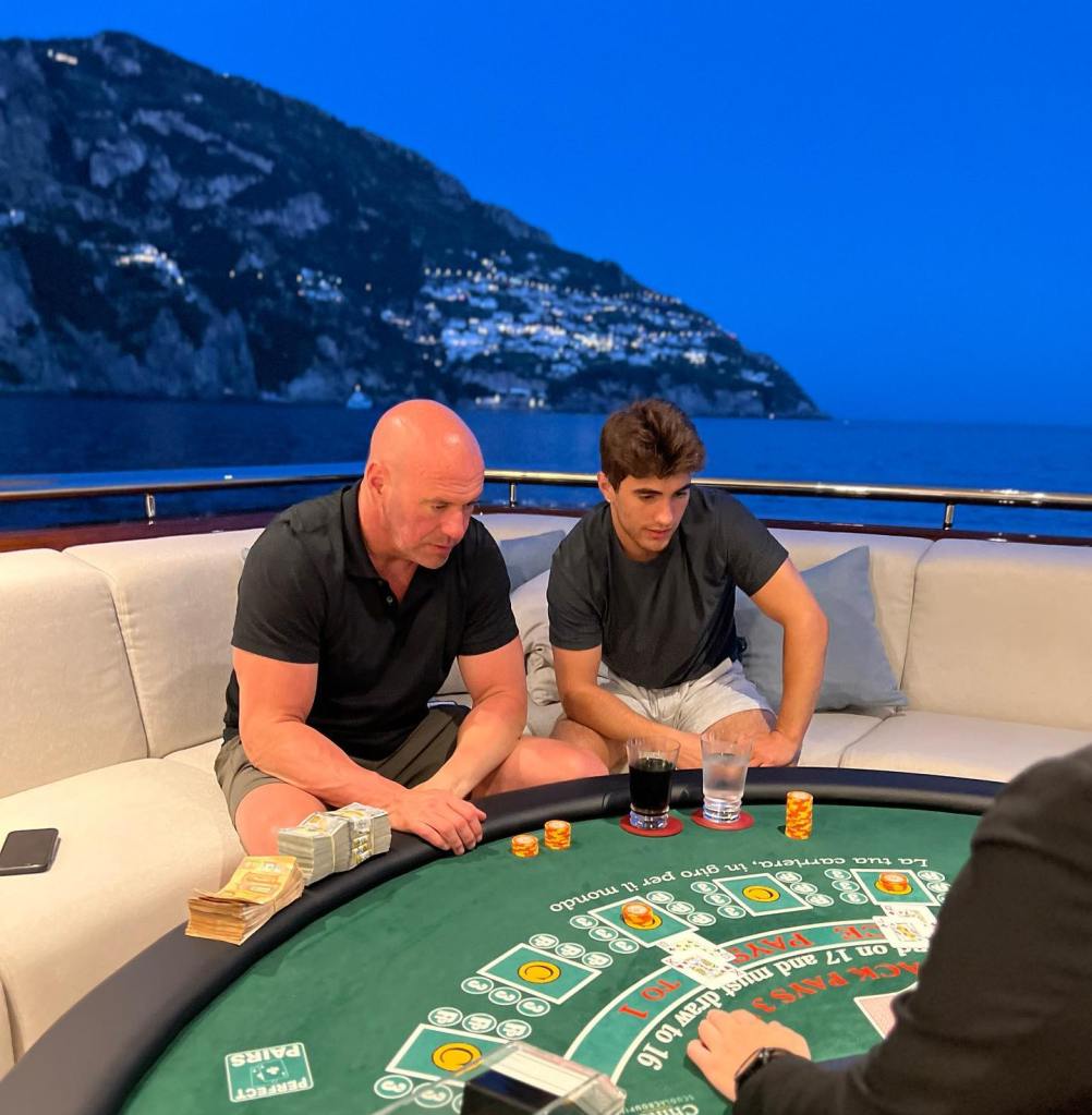 Dana White and his son Aidan White playing cards on a boat.