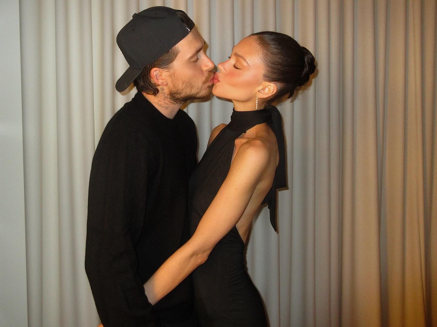 Nicola Peltz and Brooklyn Beckham kiss, celebrating their engagement anniversary.