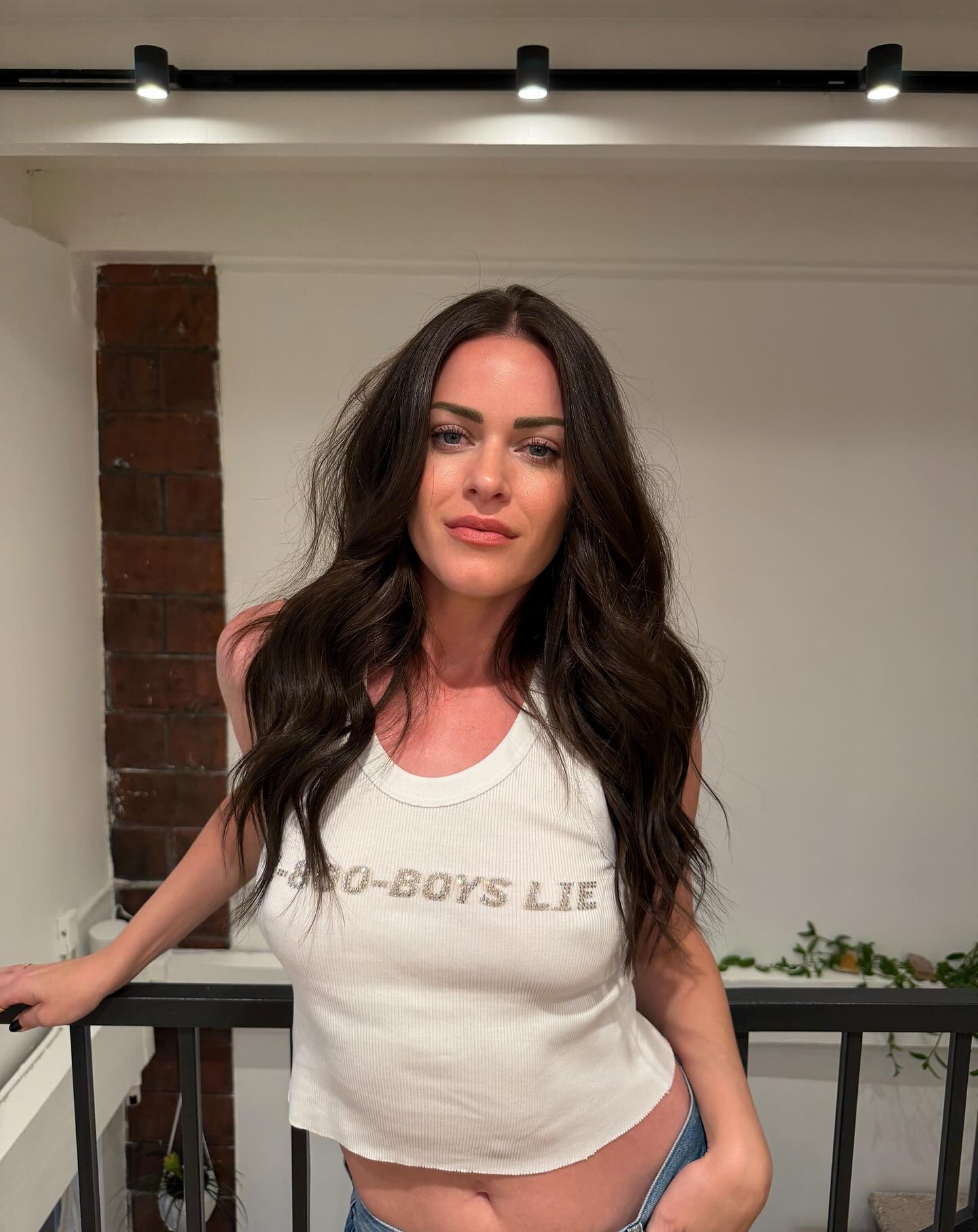 Dayna Kathan in a white tank top with "BOYS LIE" in glitter letters.