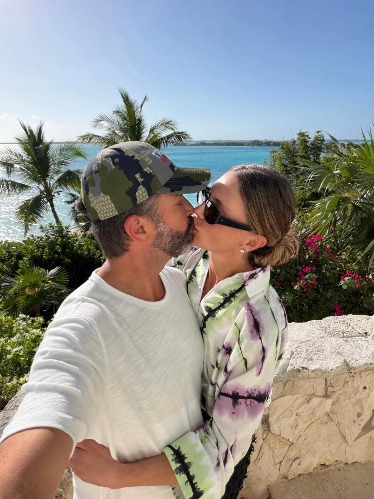 Bettina Anderson and Donald Trump Jr. kissing with a tropical ocean view behind them.