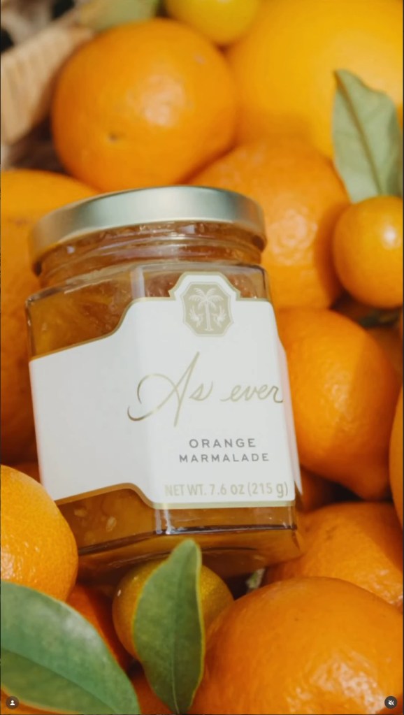 A jar of "As Ever" Orange Marmalade surrounded by fresh oranges and tangerines.