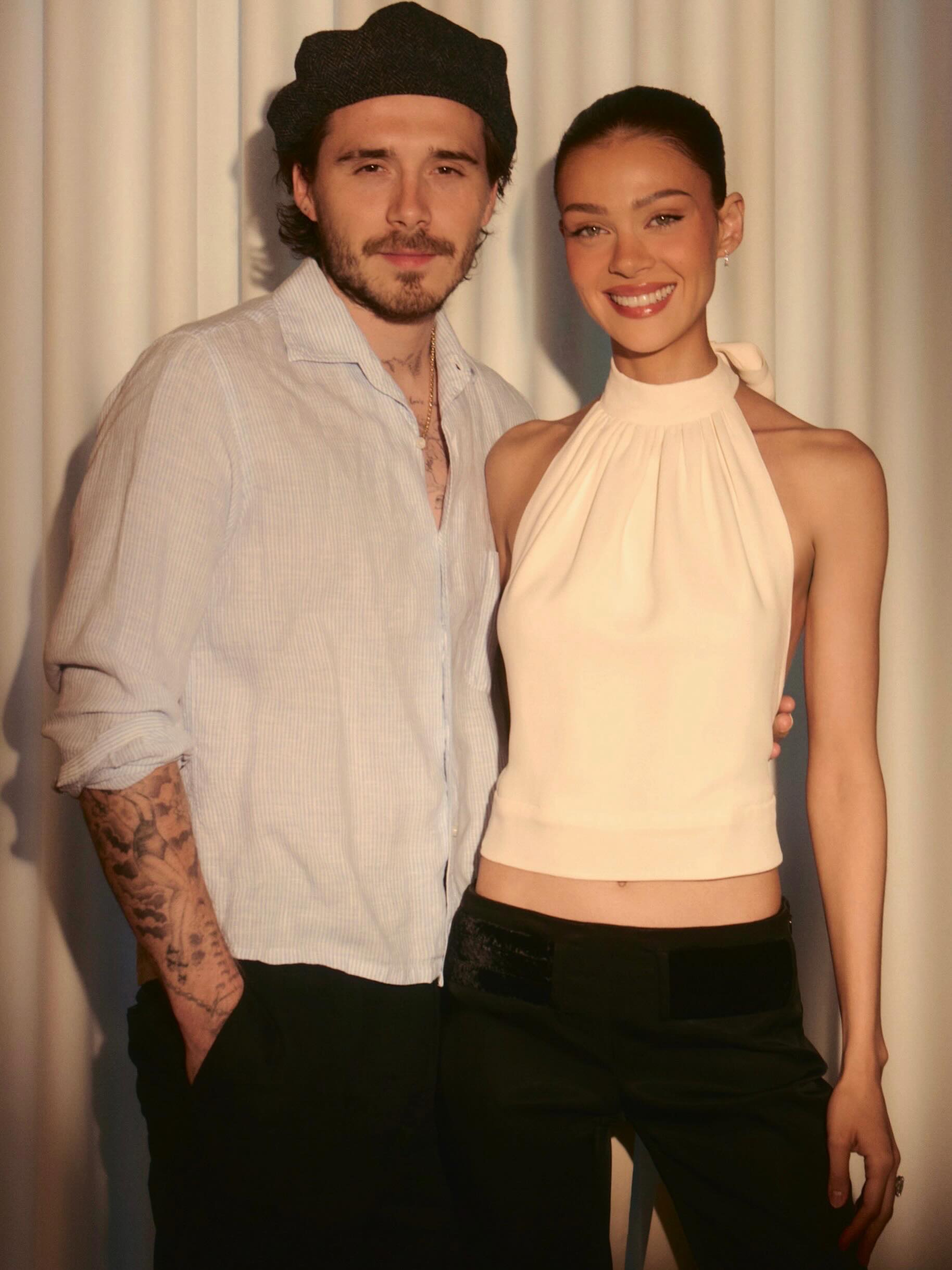 Brooklyn Beckham and Nicola Peltz standing together and smiling.