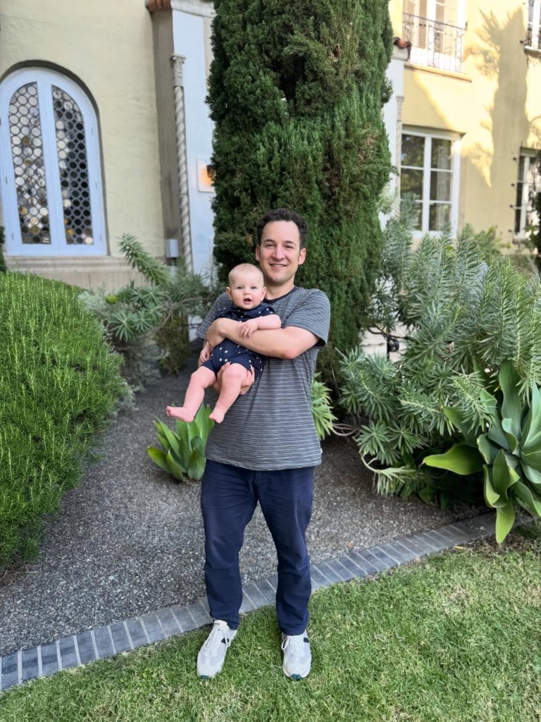 Ben Savage holding a baby outside a building.