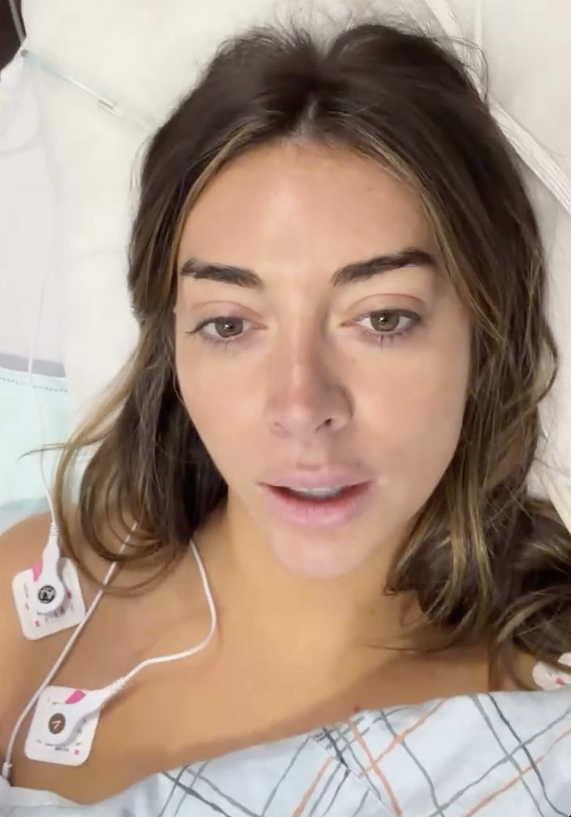 A woman lying in a hospital bed with electrodes attached to her chest after a vaginal ultrasound.