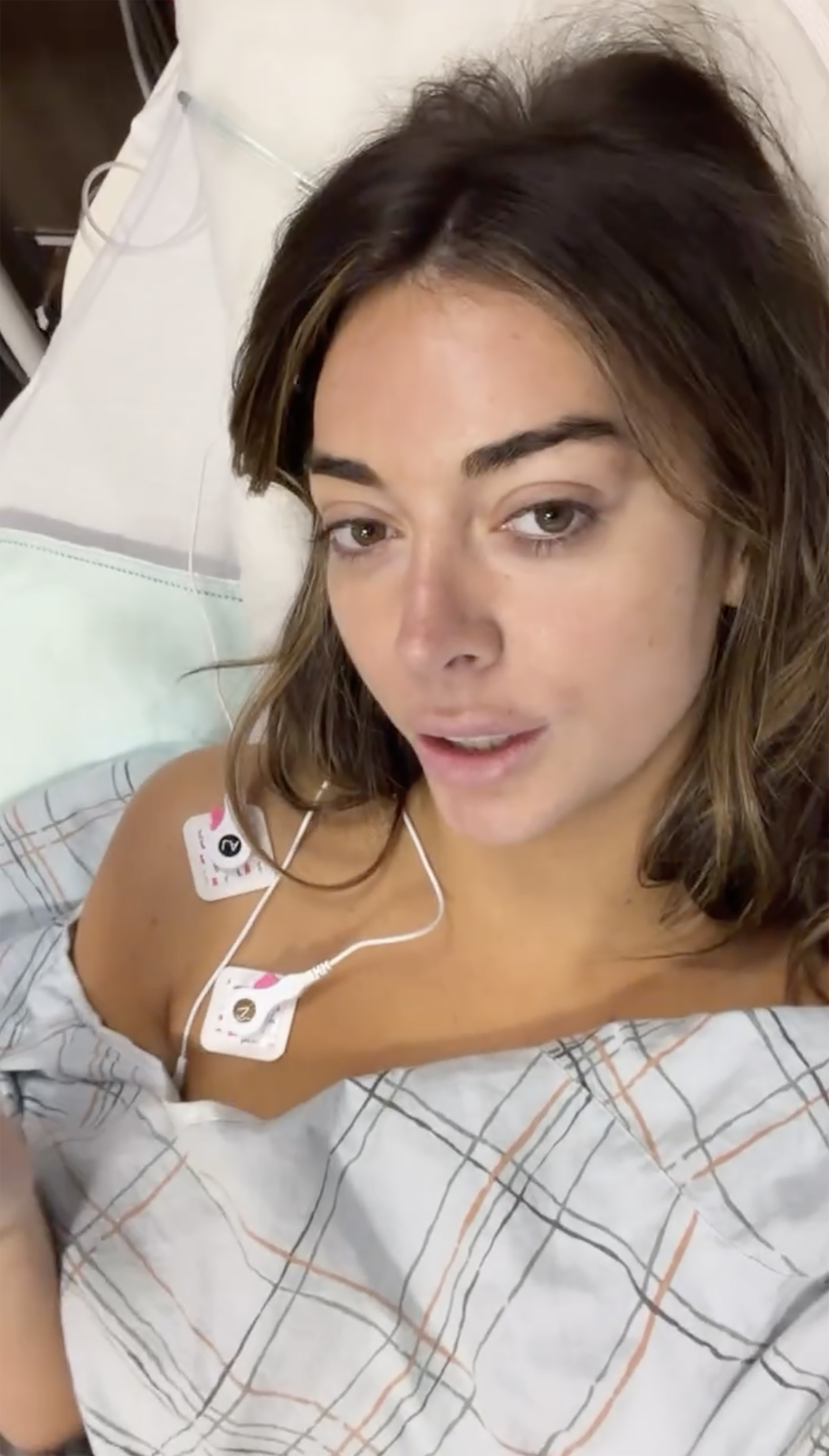 Brianna Chickenfry in a hospital bed with medical electrodes attached to her chest.
