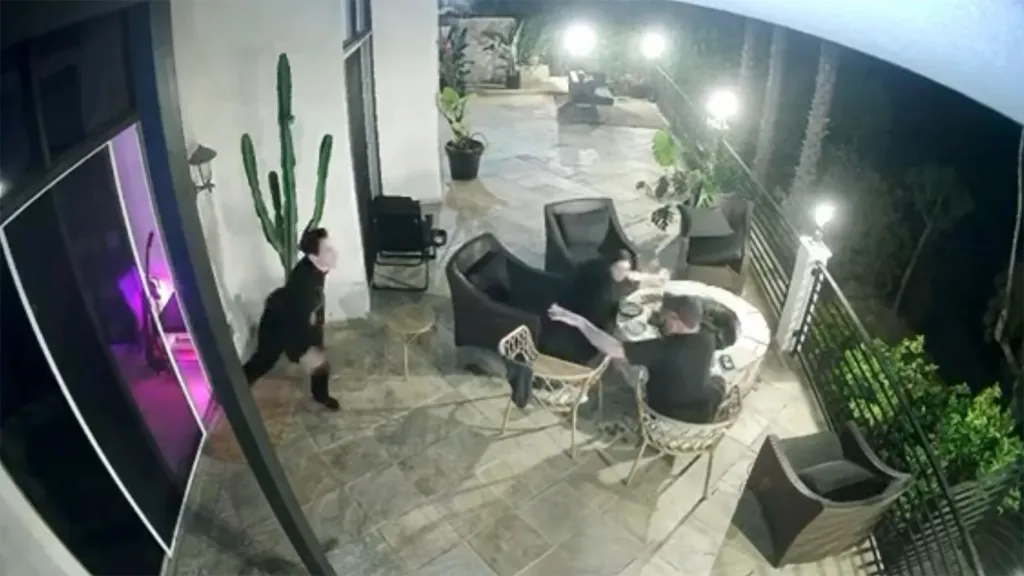 Tom Sandoval shoving Victoria's dad, who is seated by a fire pit, as he approaches.
