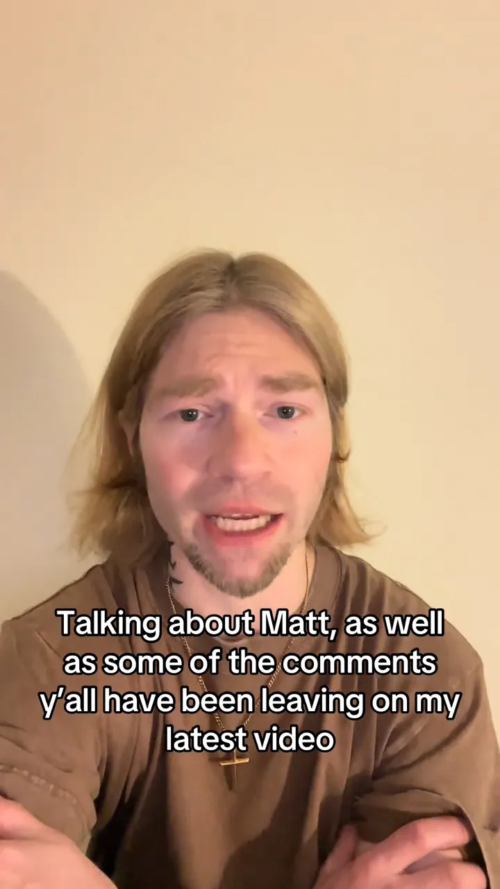 A man with long blonde hair and a beard, wearing a brown shirt and cross necklace, talks to the camera with text overlaid that reads, 
