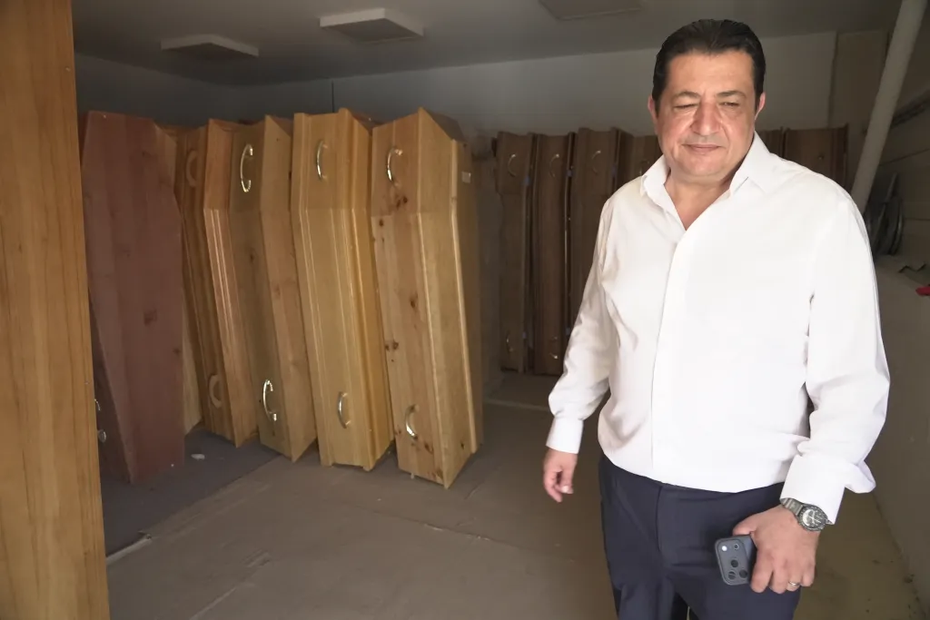 Zouhaeir Hertelli, a mortuary and funeral service director, stands in a storeroom filled with coffins.