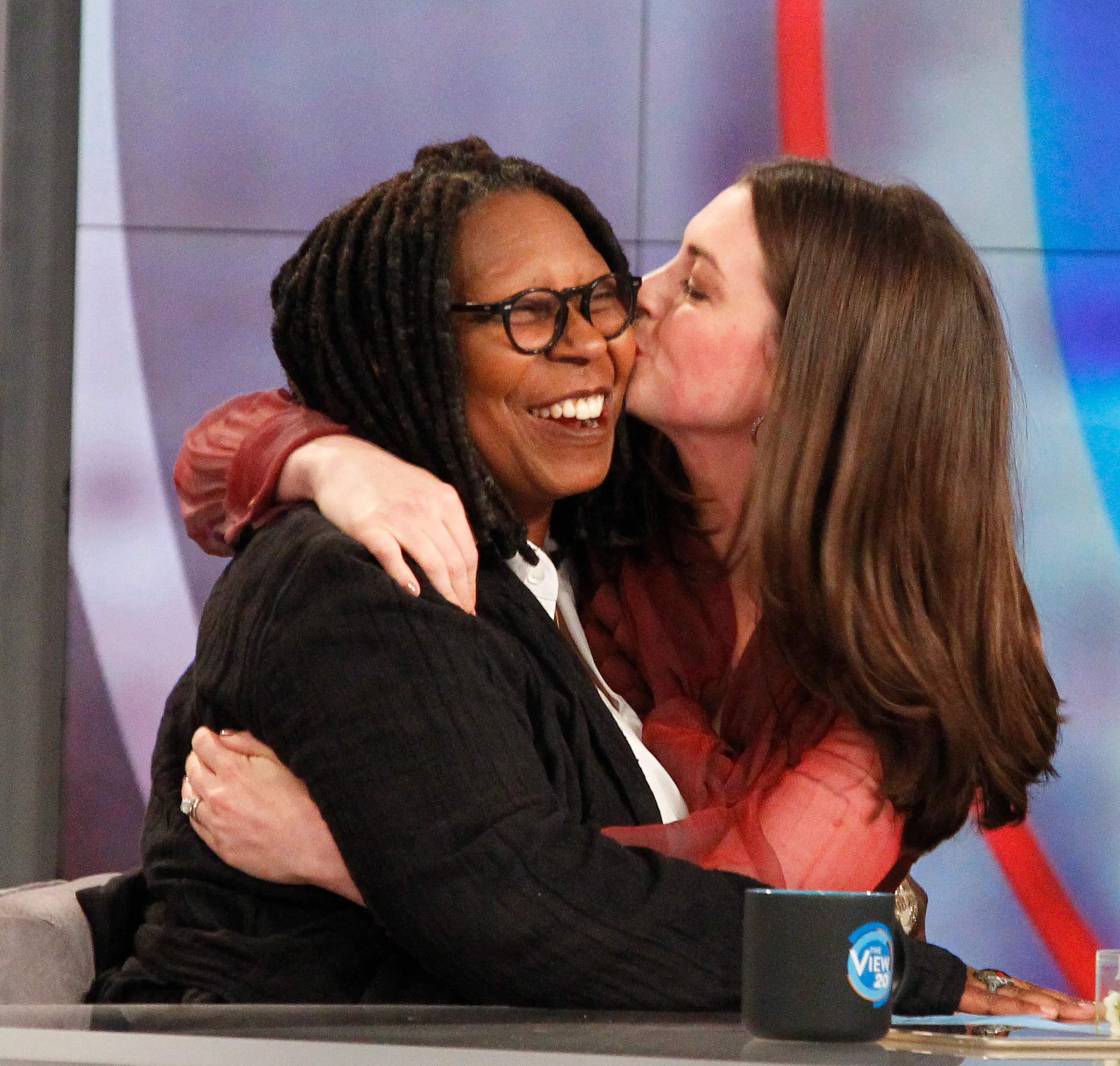 Anne Hathaway kissing Whoopi Goldberg on the cheek during an episode of "The View".
