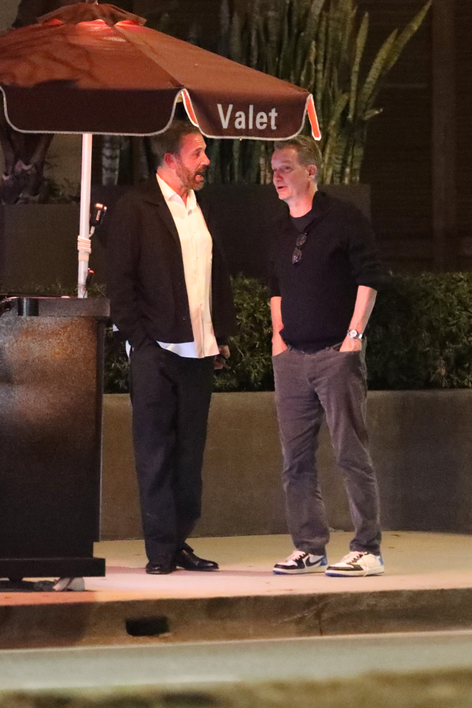 Ben Affleck talking with Sean Bailey outside Baltaire restaurant under a "Valet" umbrella.