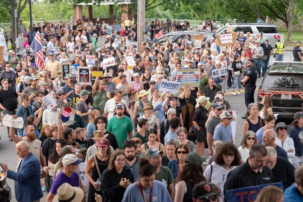 A large group of protestors marching with signs against ICE.