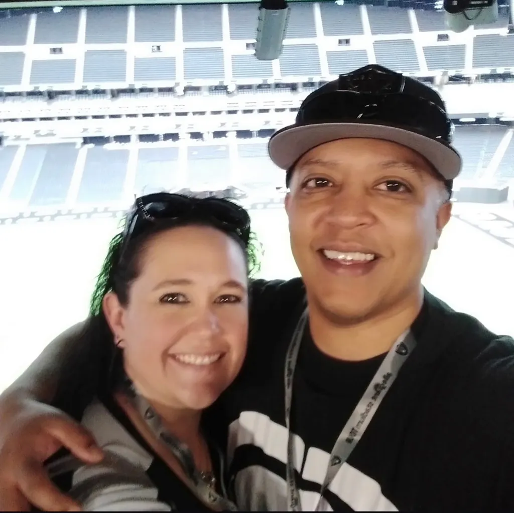 A man and a woman smiling at a stadium.