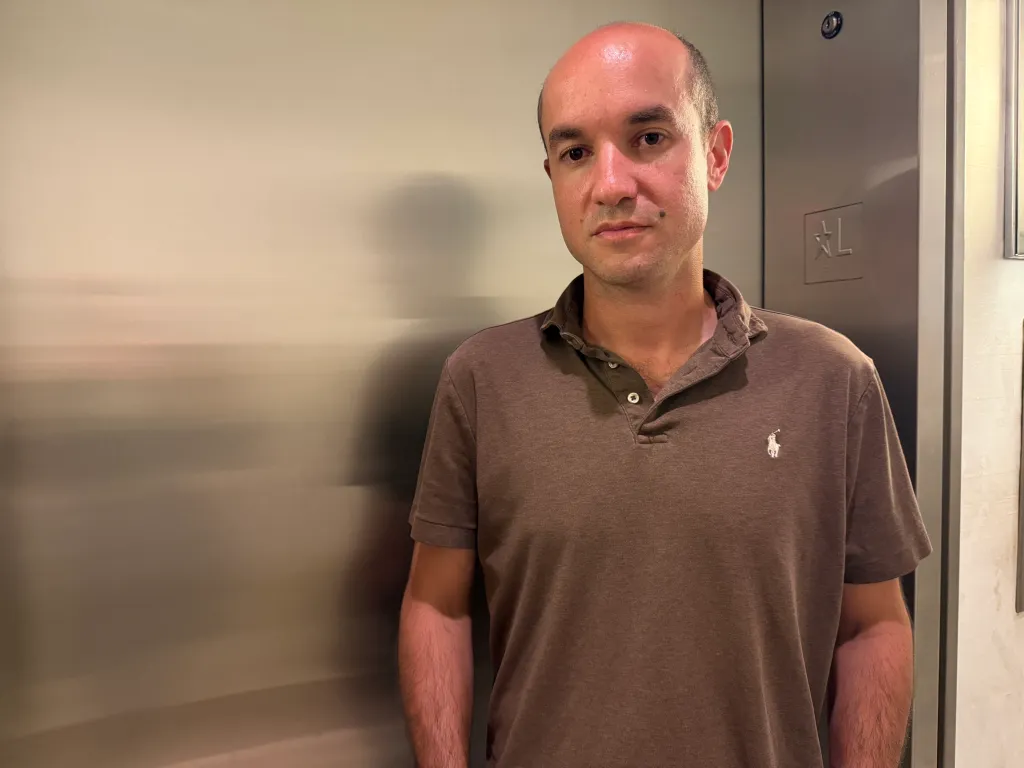 Matt Aaron, head of the tenant association, stands in front of an elevator.