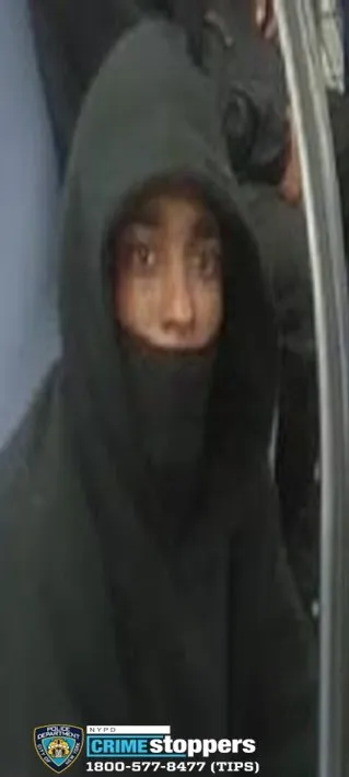 Photo of a robbery suspect wearing a black hoodie and black face covering, with only their eyes and the bridge of their nose visible.