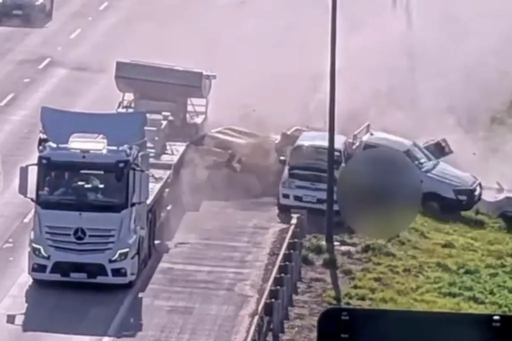 A Mercedes-Benz truck carrying a heavy load collides with another vehicle, causing debris to fly into the air.