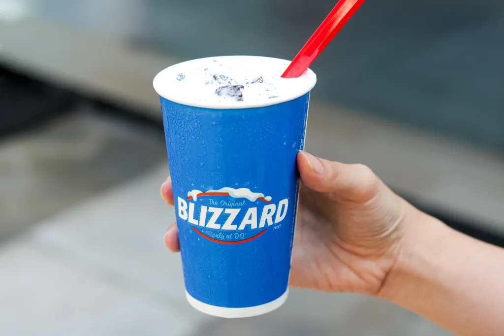 Hand holding a Dairy Queen Oreo Blizzard with a red spoon.
