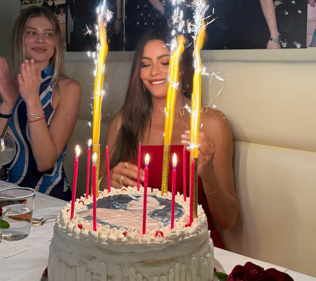 Sofia Vergara celebrating her birthday with a cake featuring her image, surrounded by candles and sparklers.