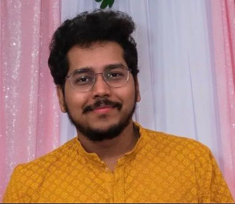 Mani Chandra Teja Gaddam, a man with a mustache and glasses, wearing a yellow shirt.