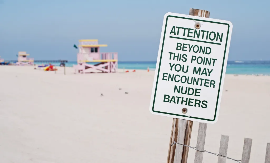 A sign that says: Attention: beyond this point you may encounter nude bathers
