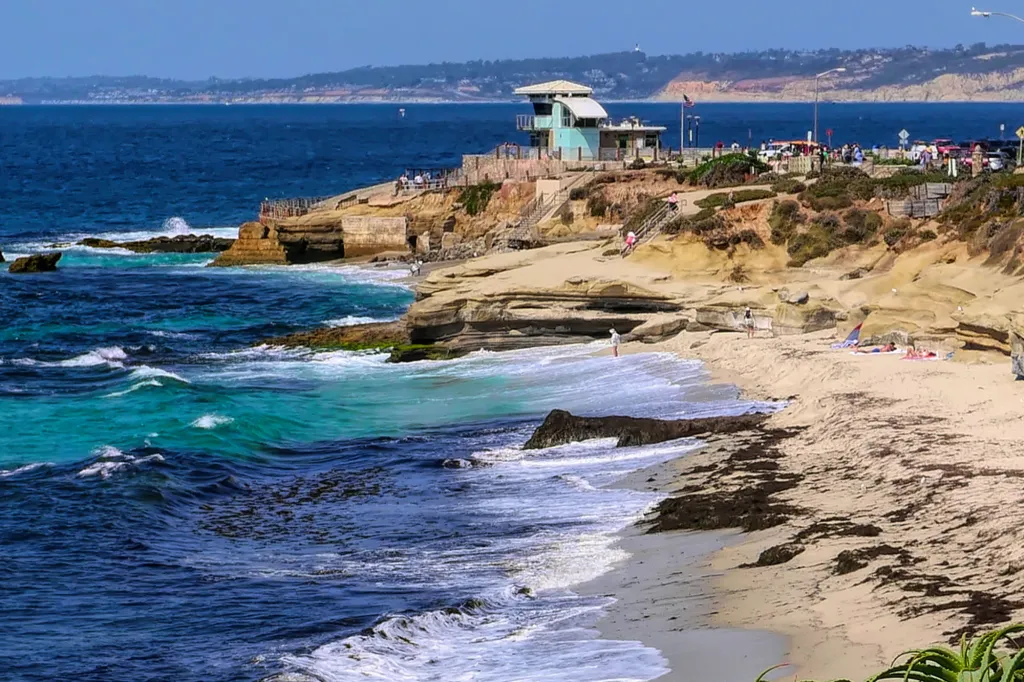 A beach in La Jolla, California, with a lifeguard station on a cliff overlooking the ocean.