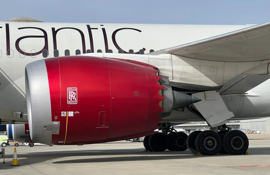 A Rolls-Royce Trent 1000 jet engine on a Virgin Atlantic Boeing 787 Dreamliner, showing the engine's red cowling and the aircraft's landing gear.