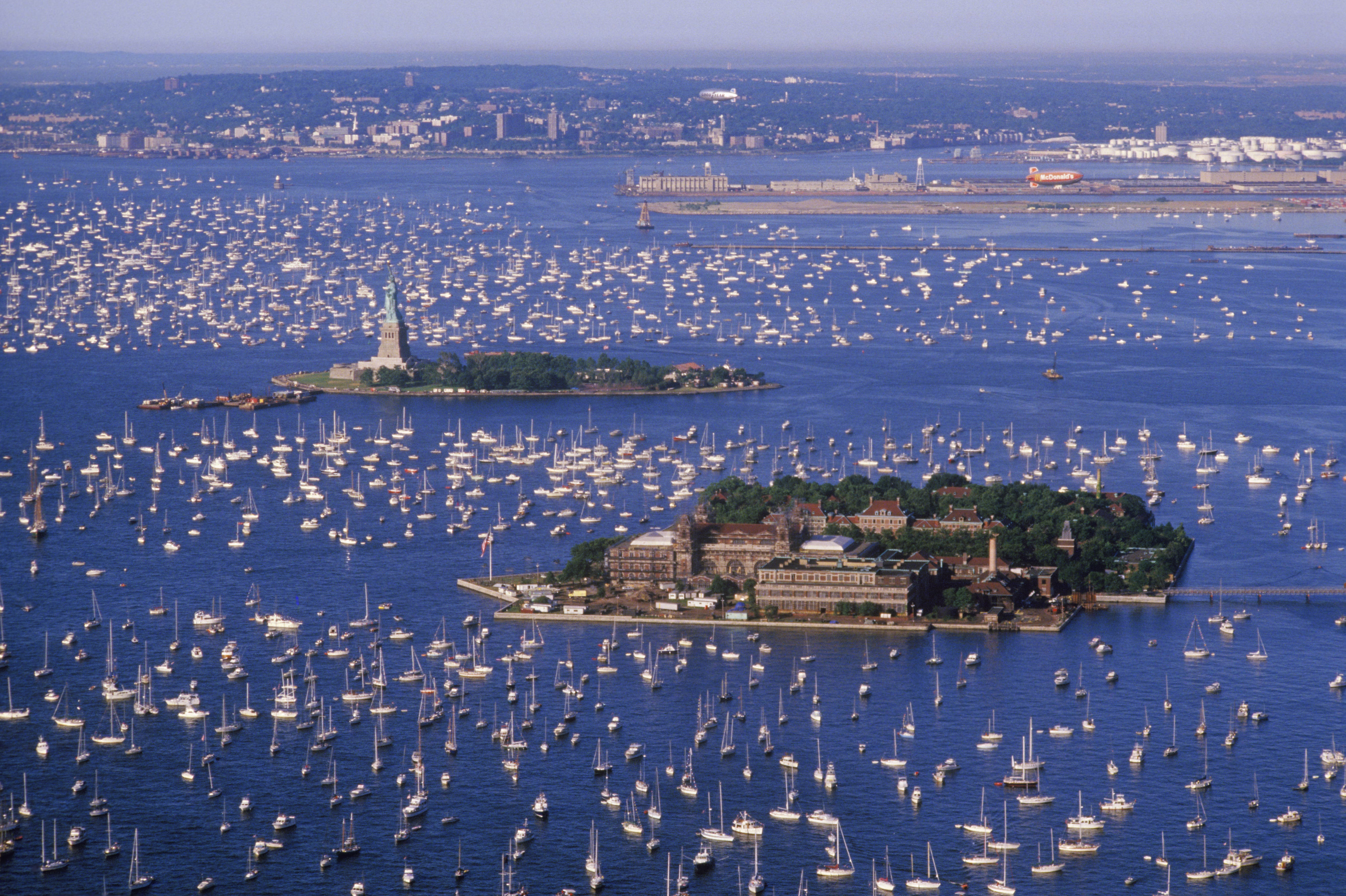 Thousands of small boats float together near the Statue of Liberty during a festival.
