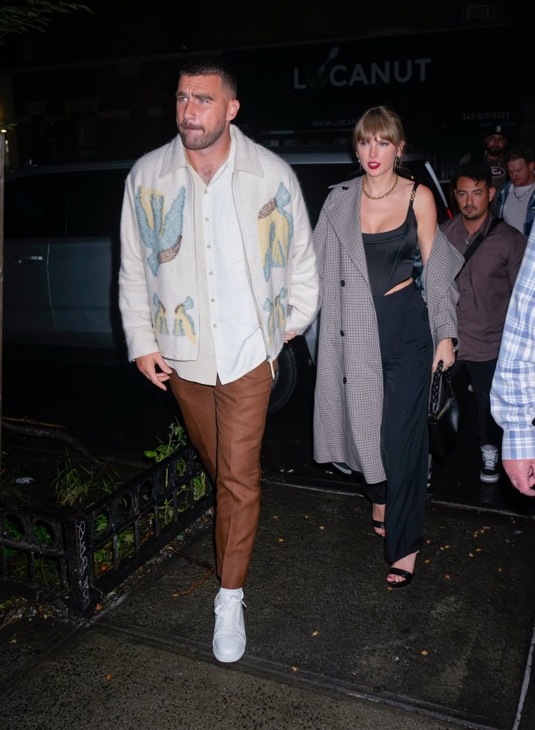 Taylor Swift and Travis Kelce walking at night.