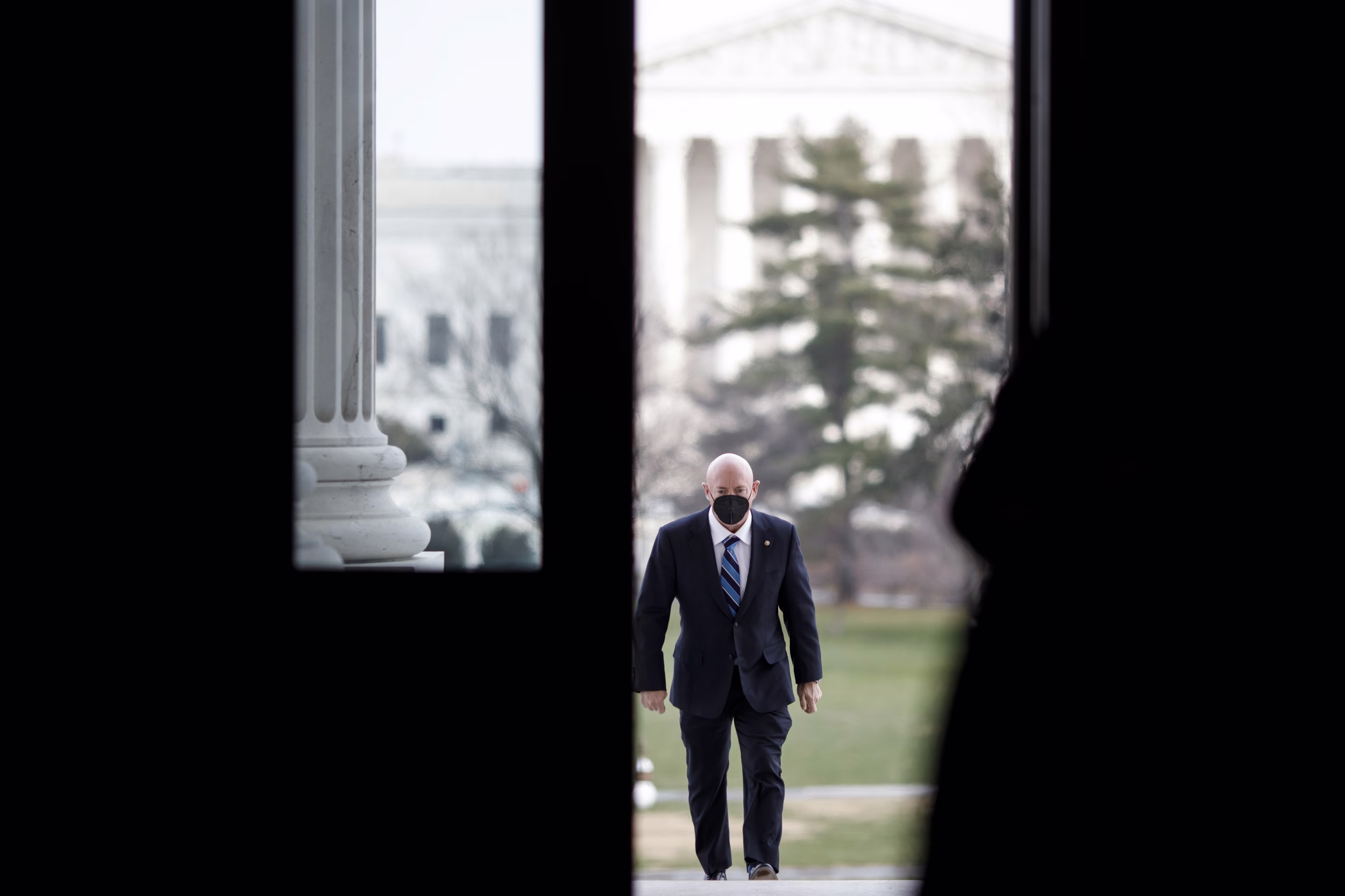 a man walks in DC with a suit on and a mask on his face
