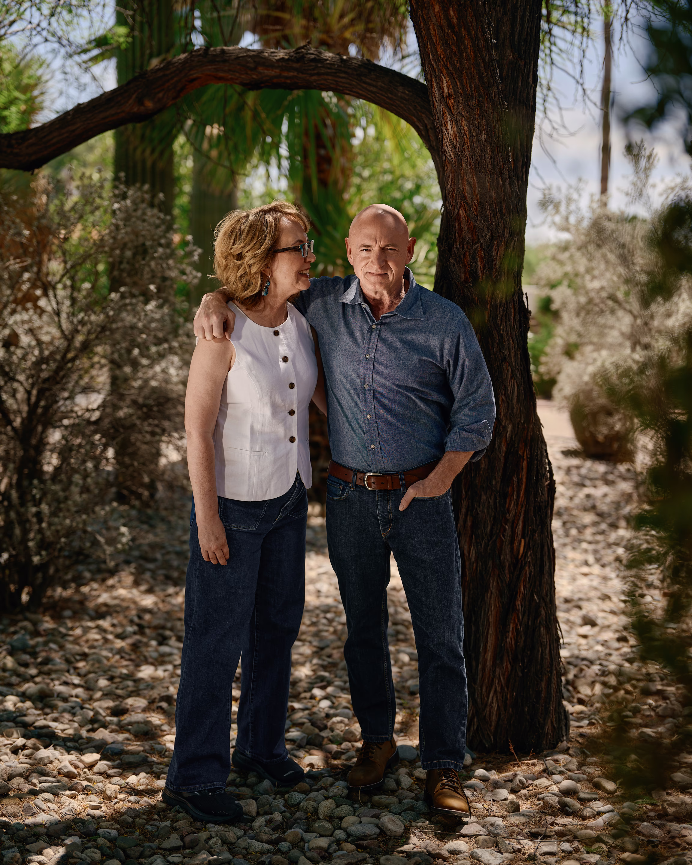 a woman and man stand together in front of a tree