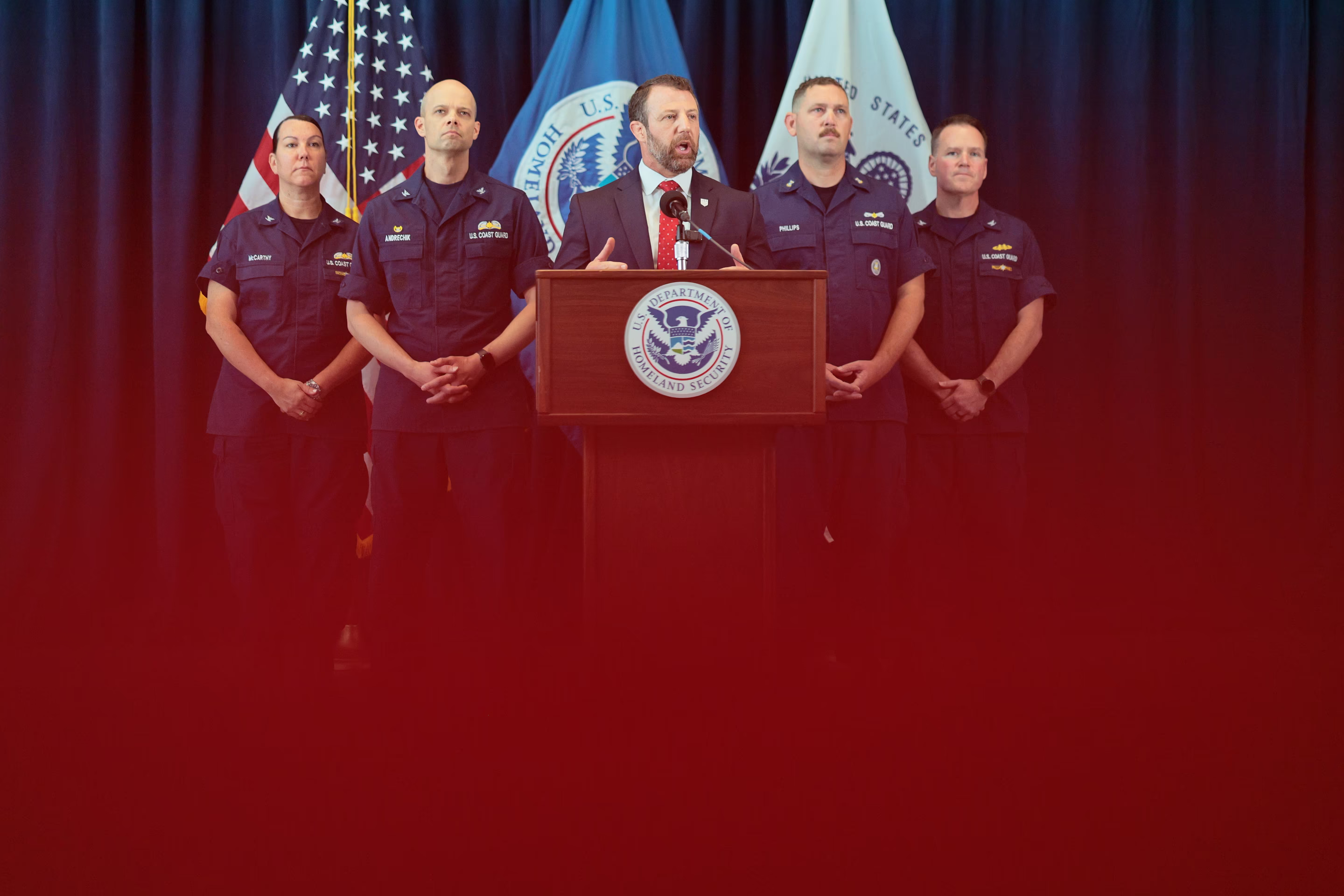 a man speaks at a podium with law enforcement behind him