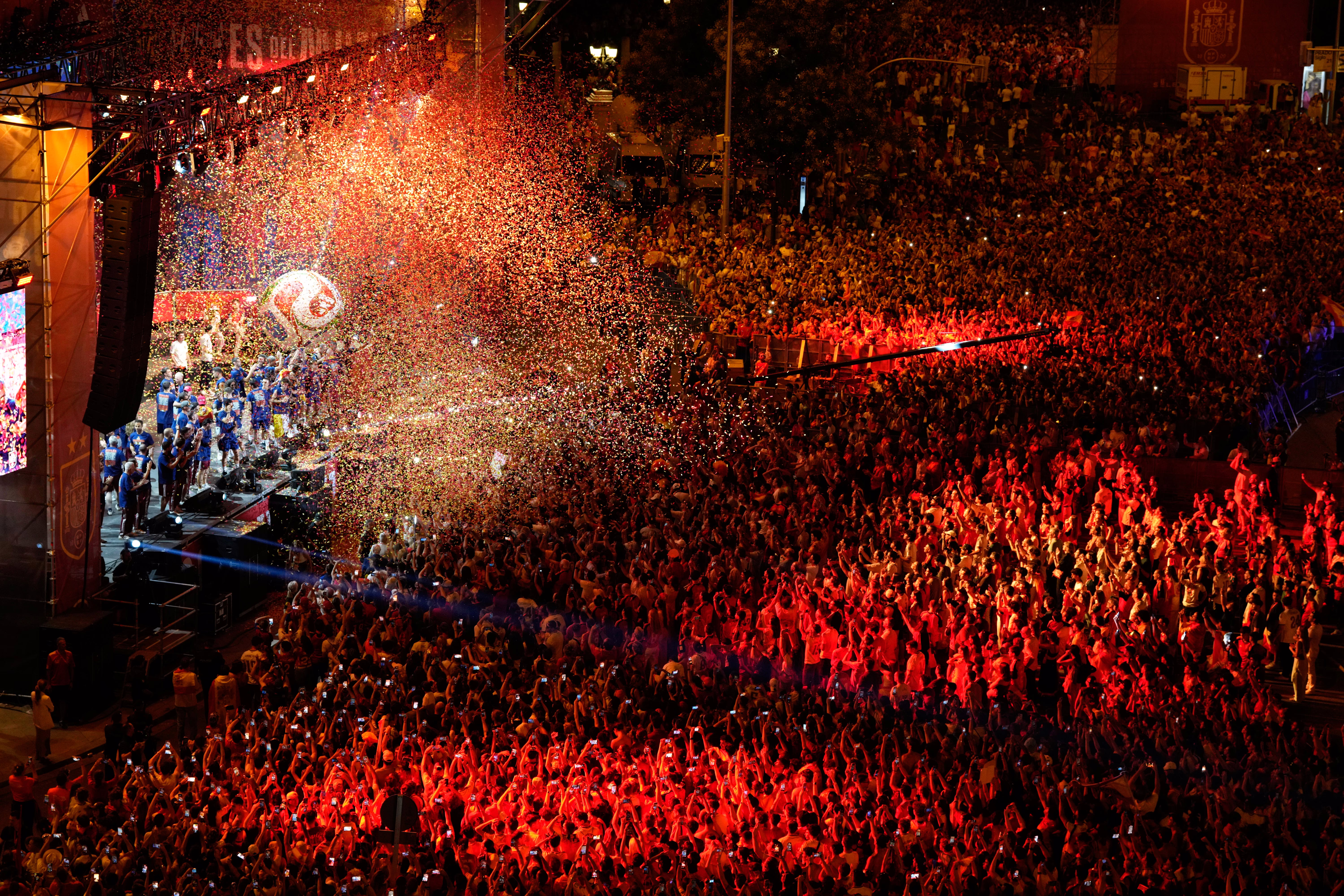 A large crowd of supporters celebrate with Spain's national football team, who stand on a stage.