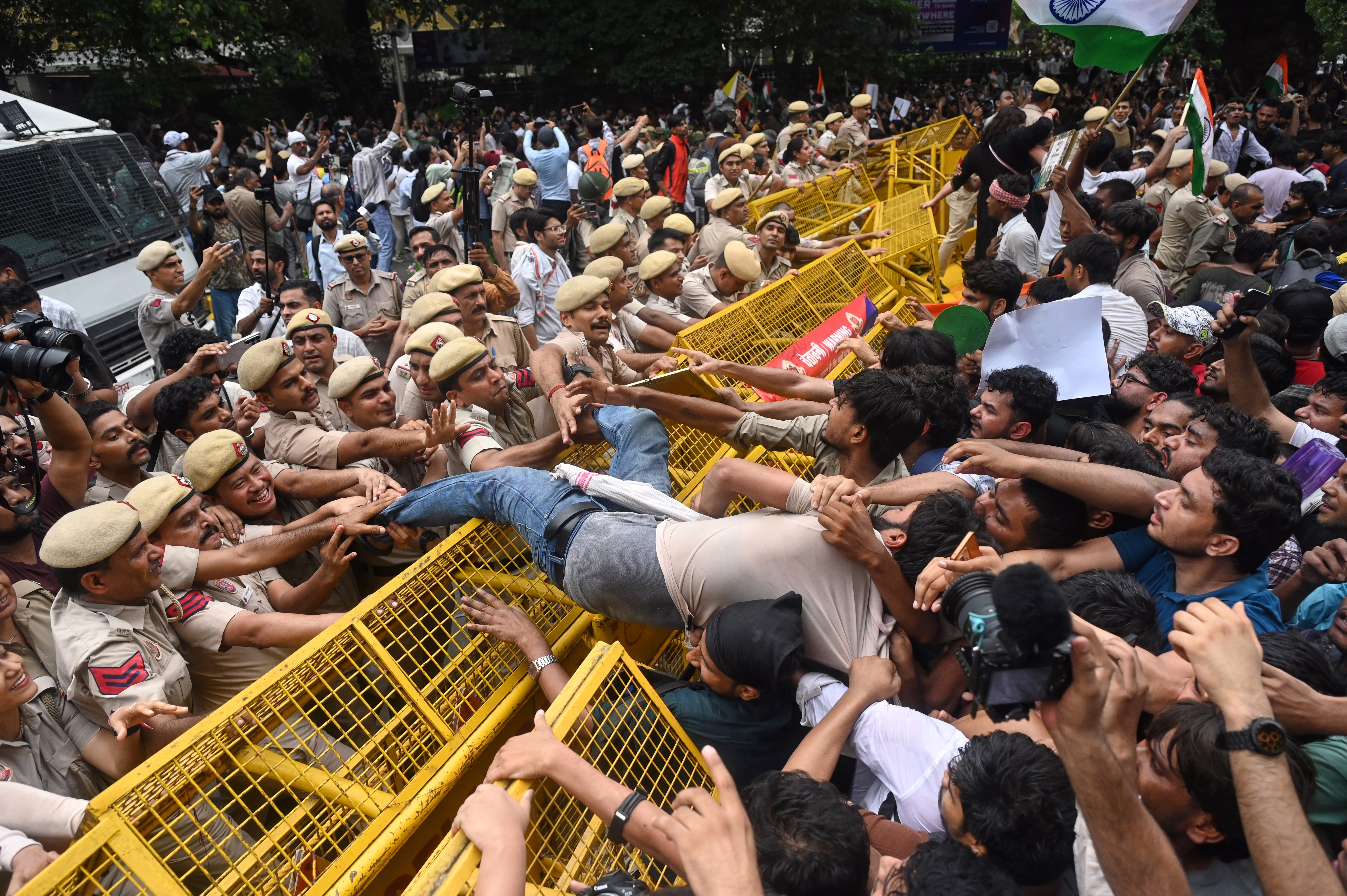 Protesters and police scuffle in India, pushing against fencing that separates them.