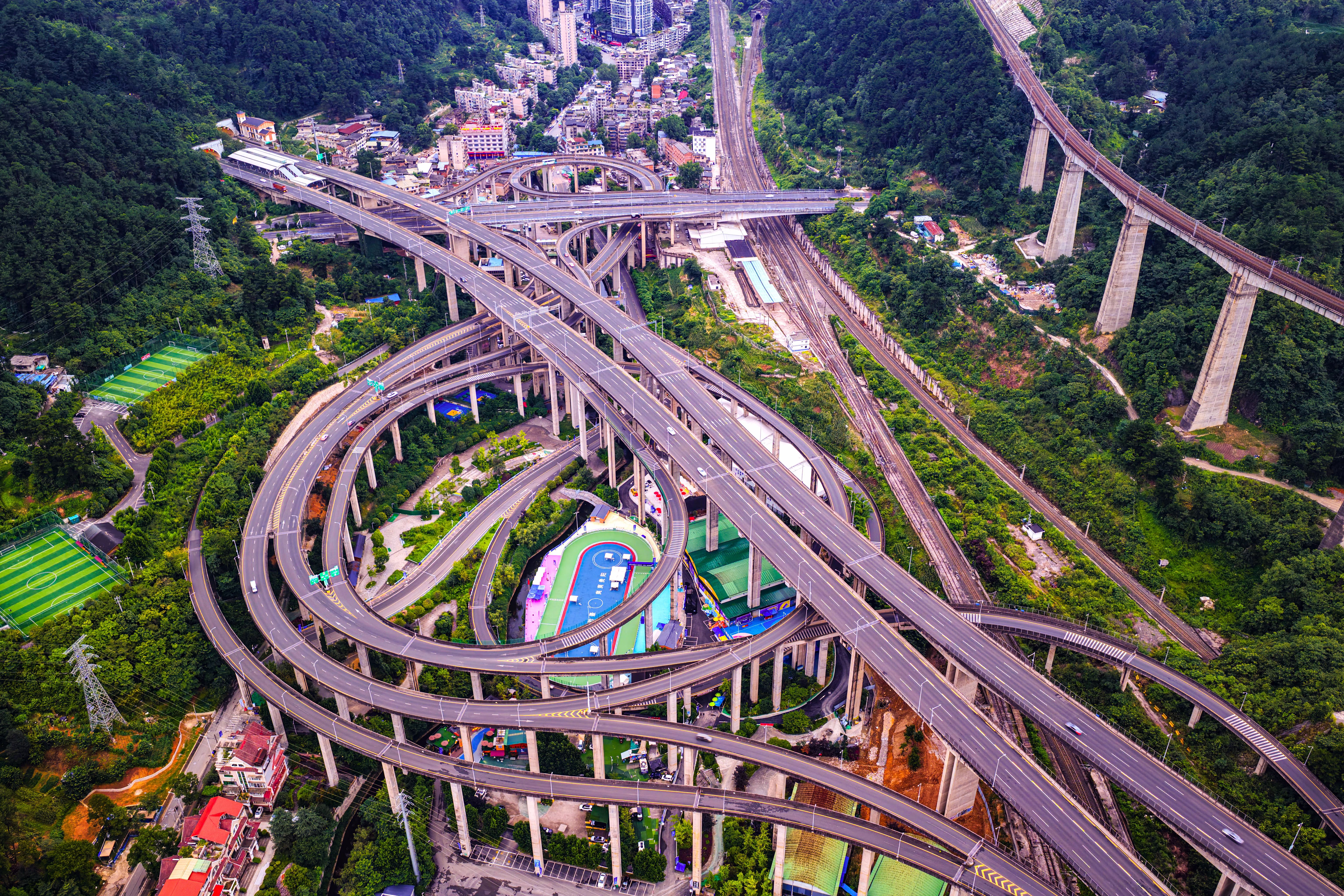 An aerial view of a complex and looping highway interchange in a narrow valley