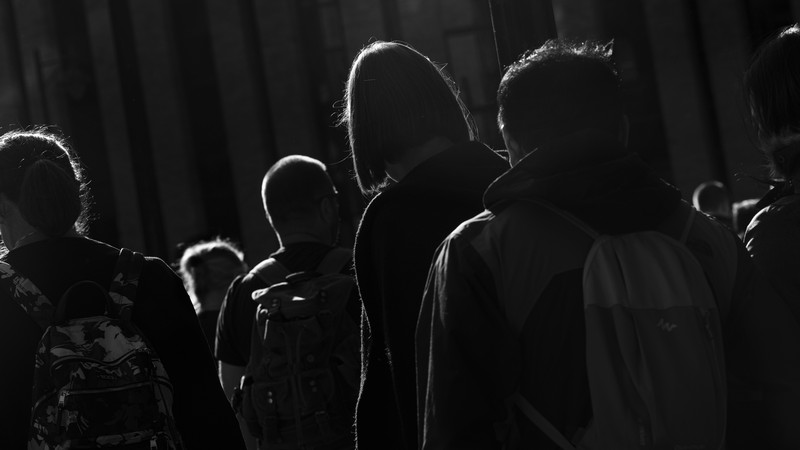 Silhouettes of people lined up in a dark street