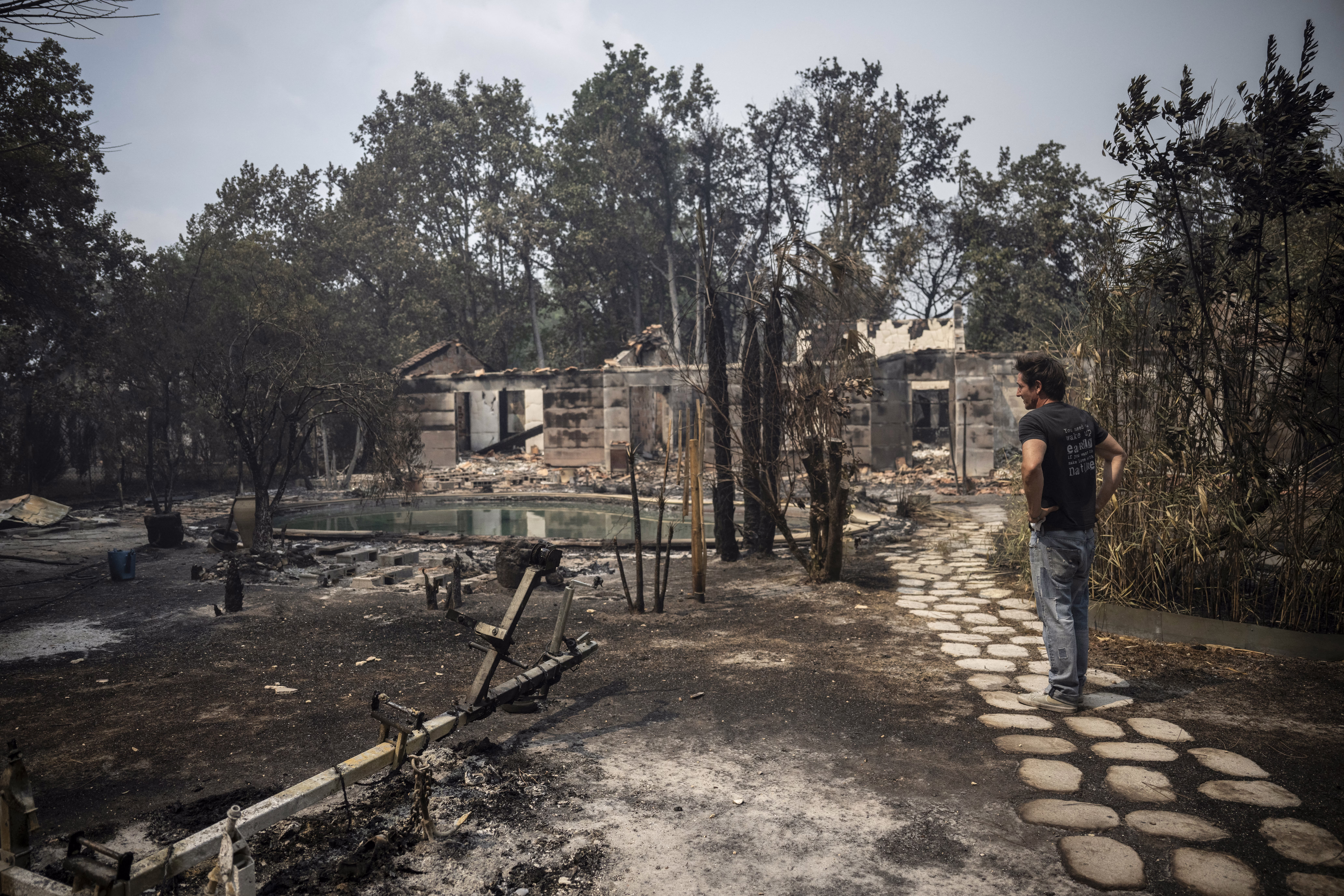 A person inspects the damage in a burned residential area.