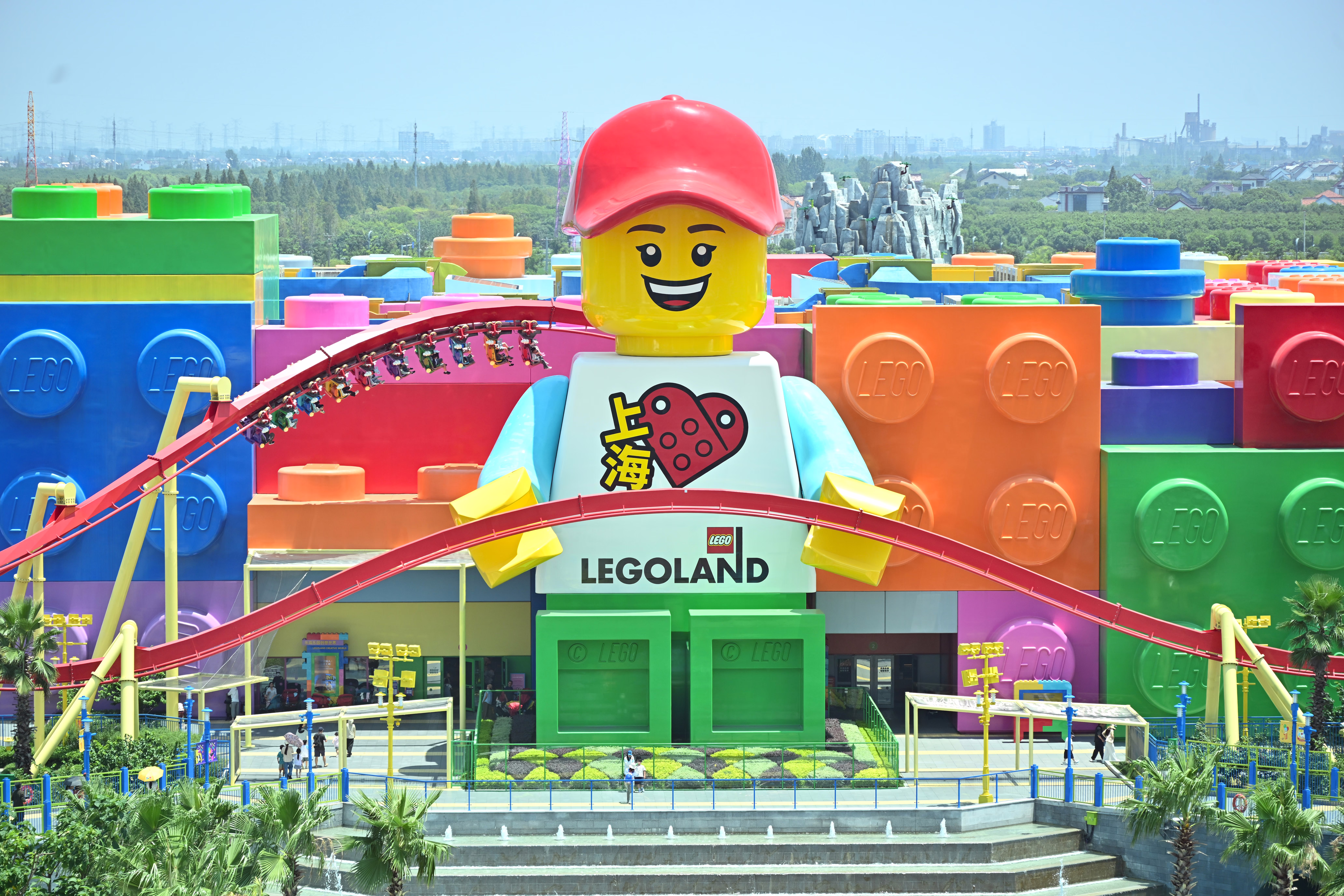 People ride a roller coaster past a giant LEGO minifig at the Legoland Shanghai Hotel.
