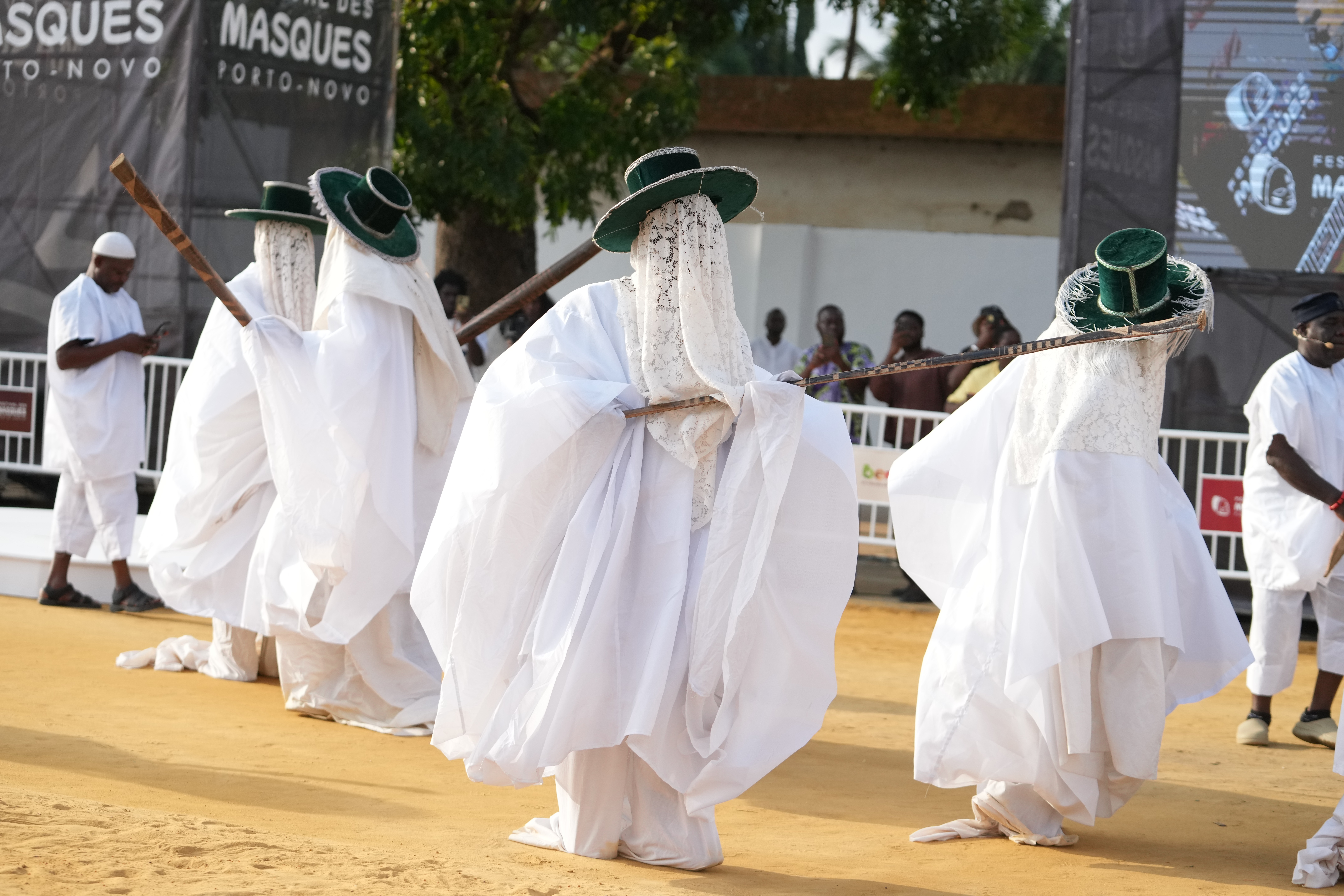 People dressed in white, flowing costumes perform during a mask festival.
