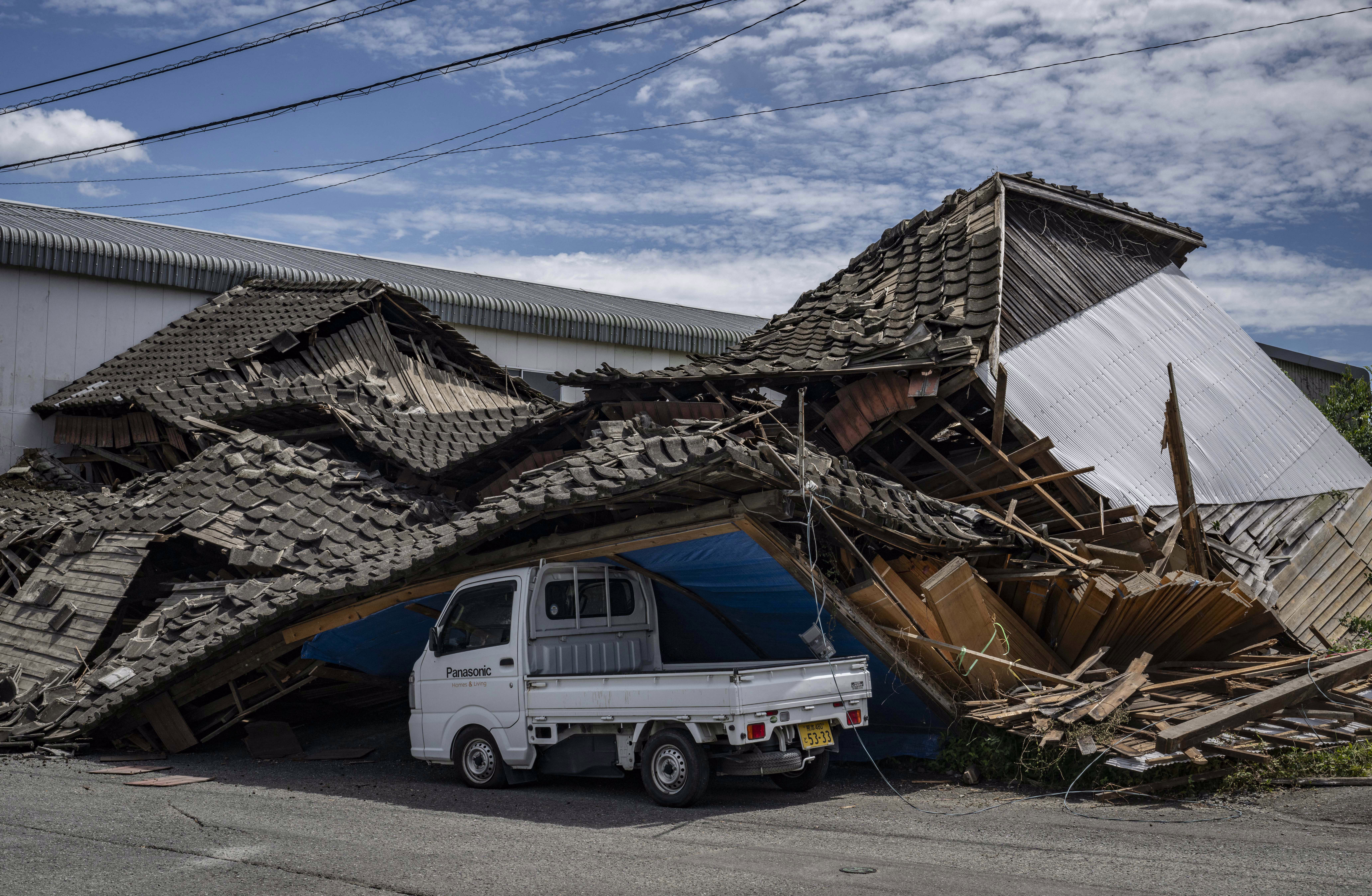 A collapsed house rests partly on a small truck after an earthquake in Japan.